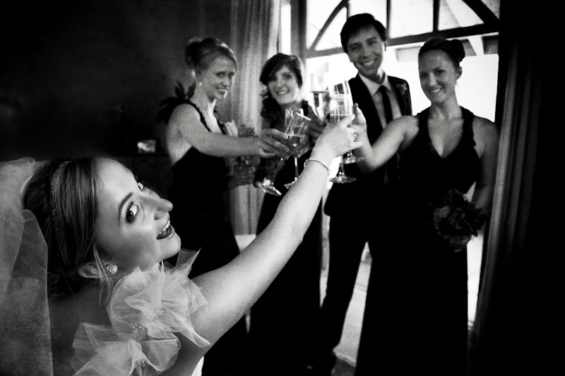 Black and white photo - bride and wedding party toasting - photo by South Africa based wedding photographer